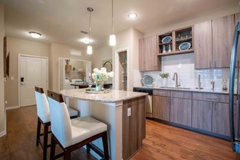 A kitchen with a bar and white chairs